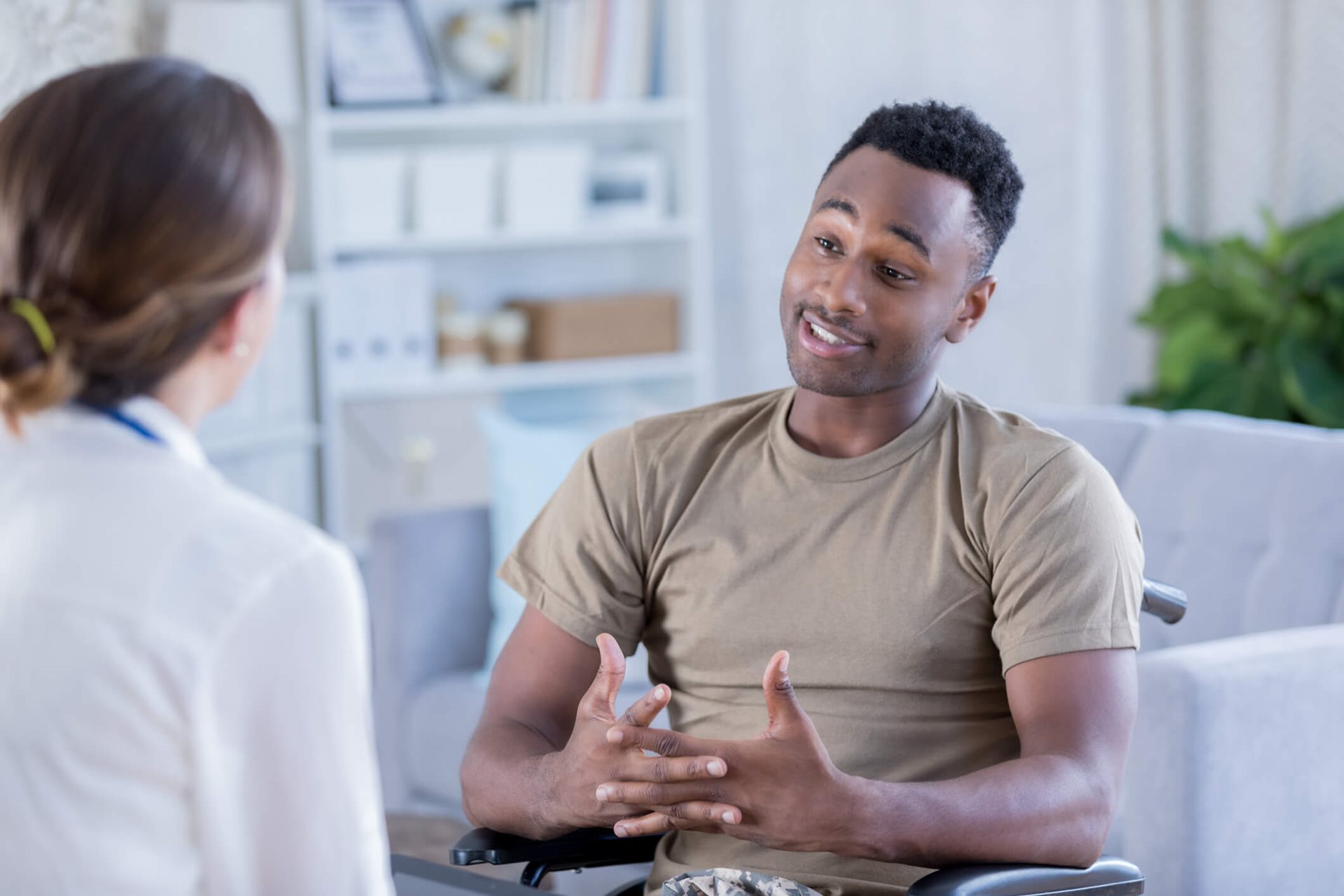 A military man in a wheelchair engages in conversation with a doctor in a clinical setting, highlighting accessibility and communication.