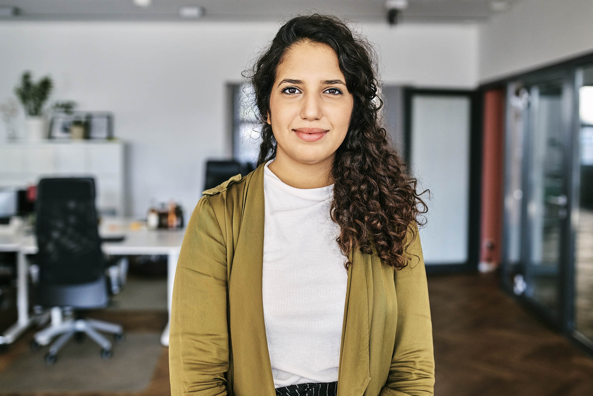 Portrait of confident young businesswoman. Female creative business professional is standing in office. She is wearing smart casual.